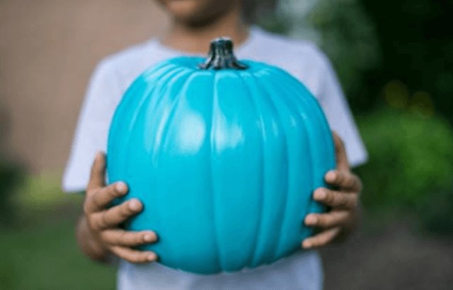 Kid holding a teal pumpkin