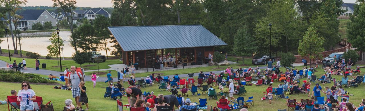 Gathering of residents on open space lawn for outdoor concert in Wendell Falls.