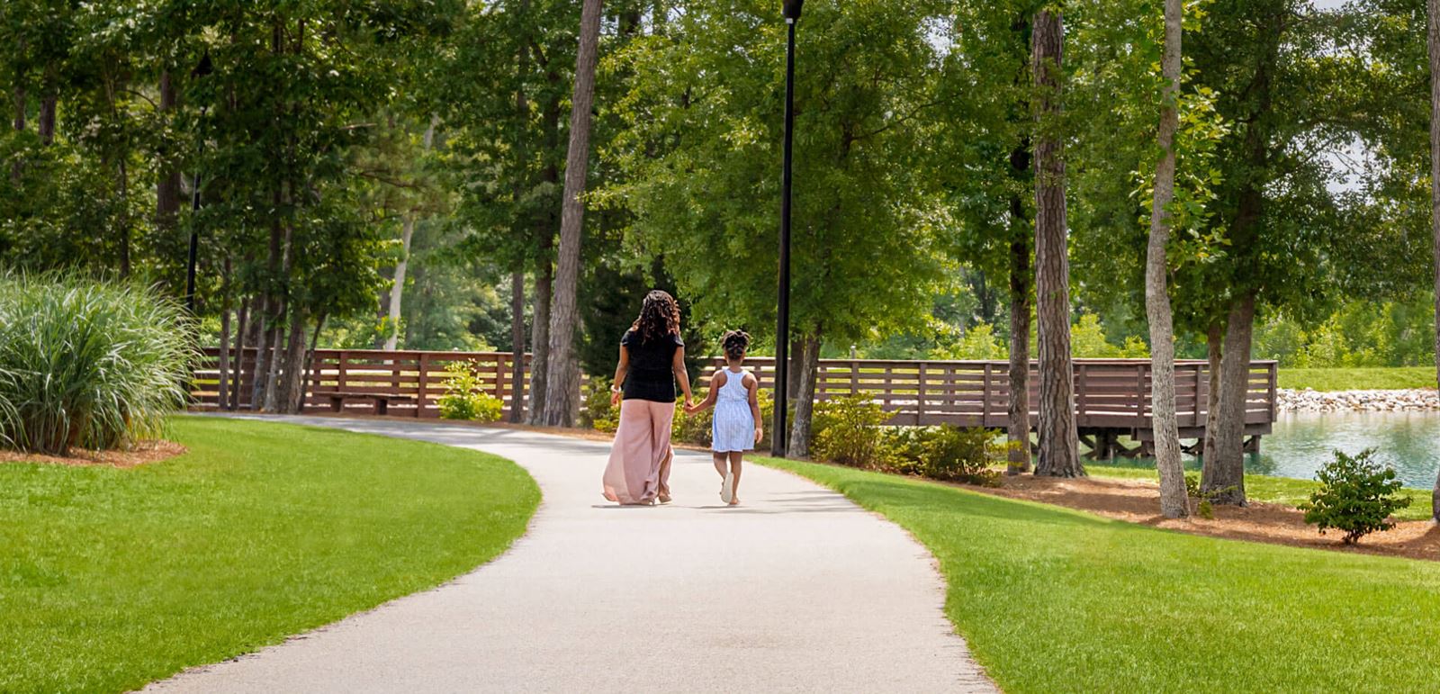 Woman and child strolling along paved trail in Wendell Falls